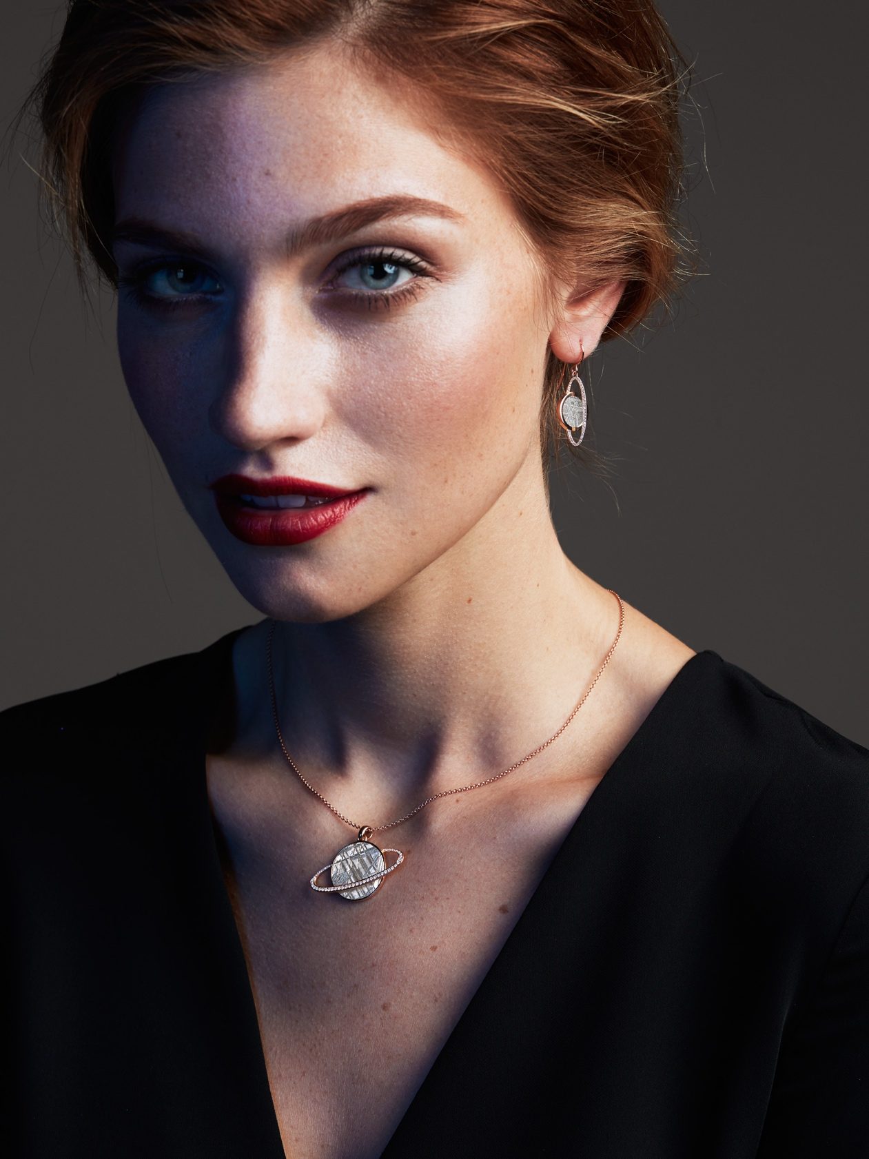 Photo d'un mannequin qui porte un pendentif et des boucles en météorites, or rouge et diamants