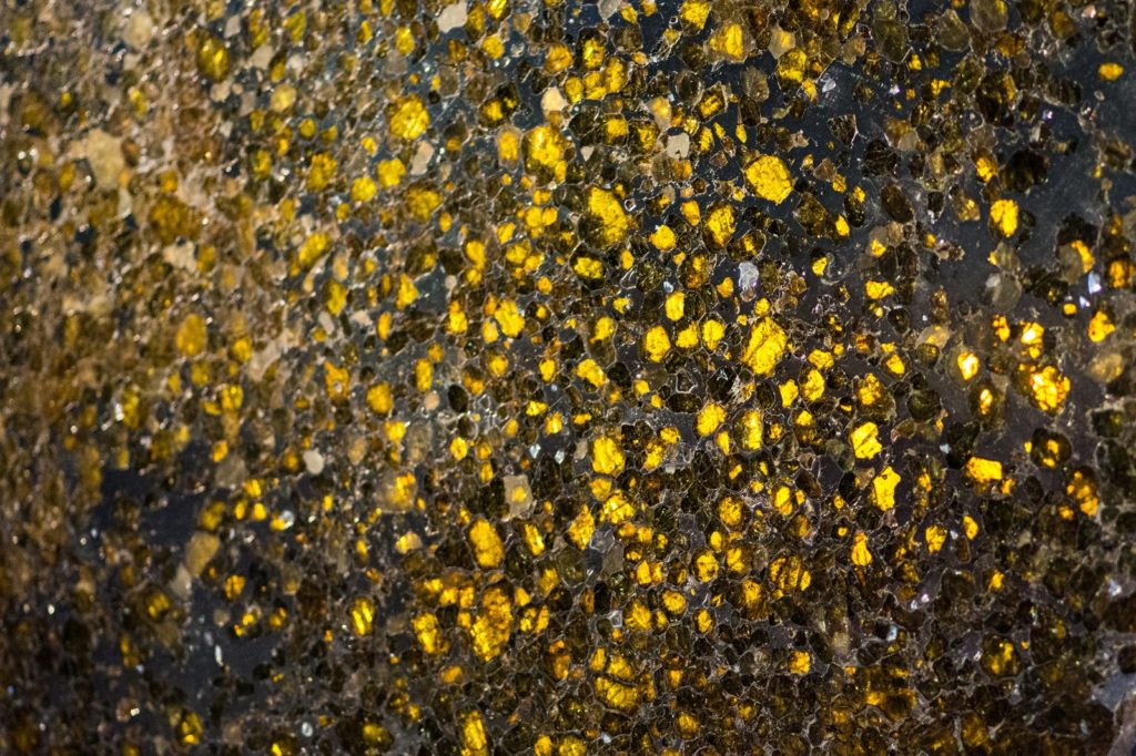 Grande tranche rétroéclairée de la pallasite Imilac aux centaines d'olivines dorées