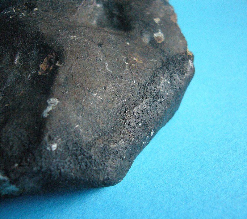Gros plan de la croûte de fusion noire et mate d'une météorite de Noktat Addagmar