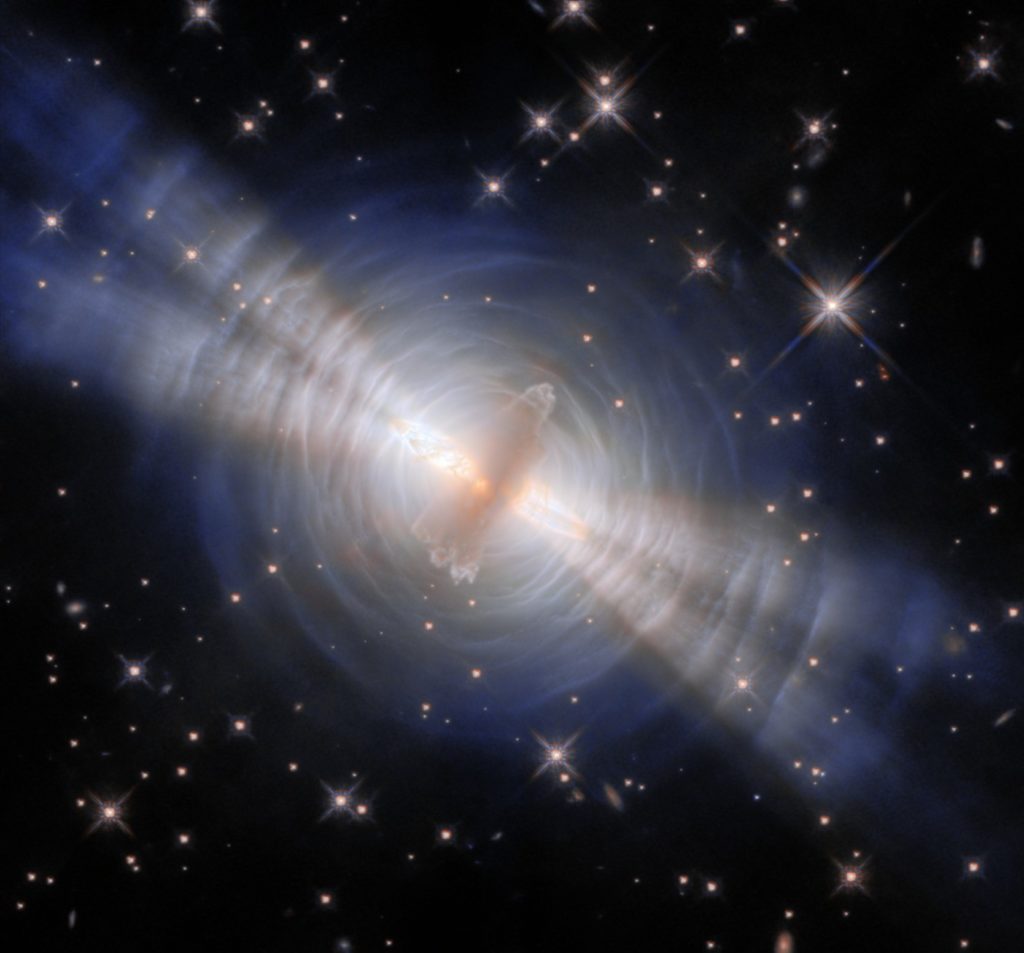 Nébuleuse de l'Œuf photographiée par le télescope spatial Hubble : deux faisceaux de lumière traversent des anneaux concentriques de poussière autour d'une étoile mourante, sur fond d'étoiles.