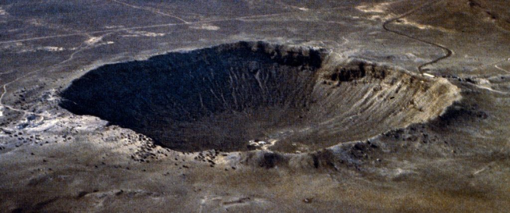 Vue aérienne oblique du Meteor Crater en Arizona : vaste dépression circulaire aux parois abruptes creusée dans un plateau désertique.
