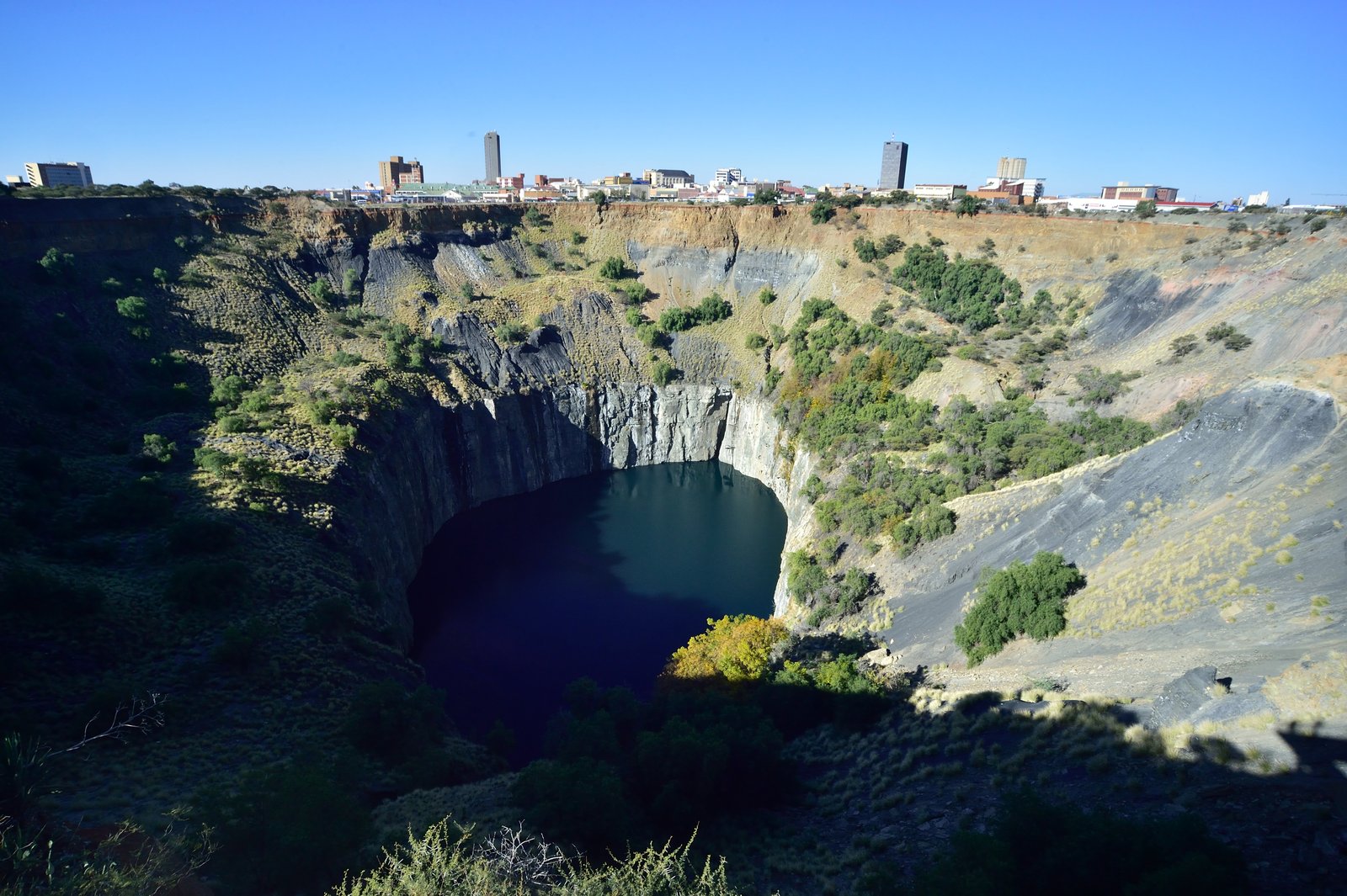 Le Big Hole de Kimberley, vaste excavation aux parois abruptes partiellement remplie d'eau, avec la ville de Kimberley à l'arrière-plan
