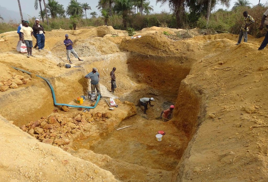 Exploitation artisanale d'un placer alluvial : mineurs dégageant la couche de graviers diamantifères sous plusieurs mètres de morts-terrains sableux dans une plaine alluviale