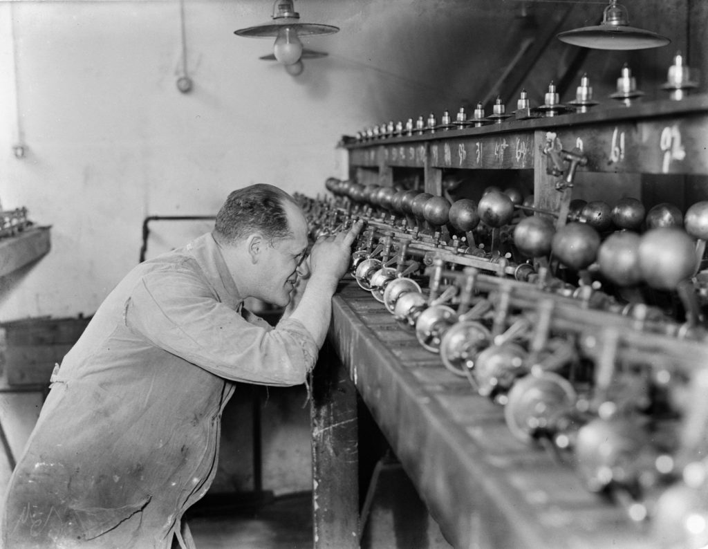 Ouvrier penché sur des rangées de machines à scier le diamant dans un atelier ancien
