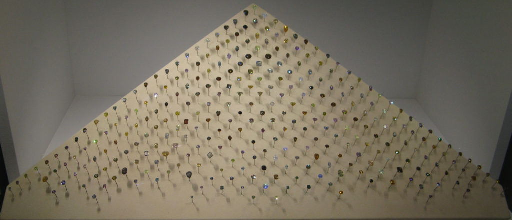 Ensemble de diamants naturels de couleur disposés en pyramide, aux teintes jaunes, brunes, vertes, bleues et roses.