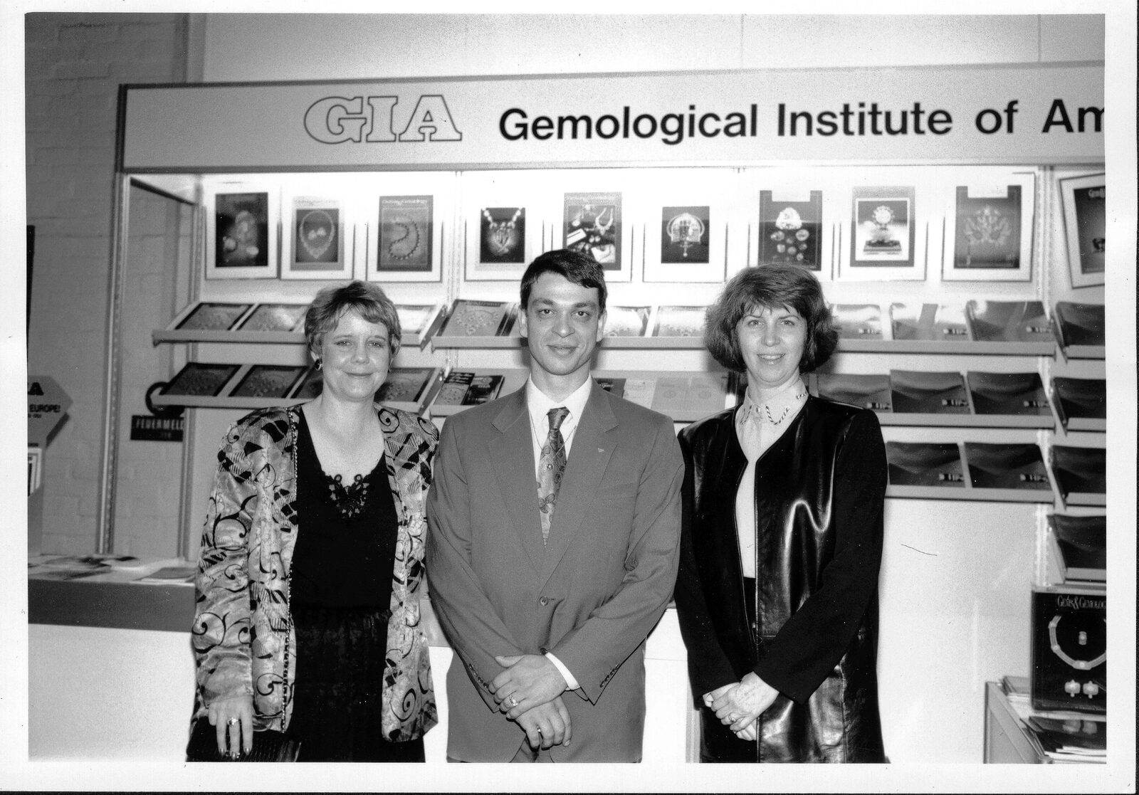 Photo noir et blanc devant le stand du Gemological Institute of America, trois personnes posant