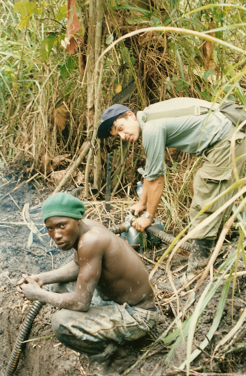 Prospection diamantifère en Guinée, deux hommes au travail dans la végétation, pompe à la main